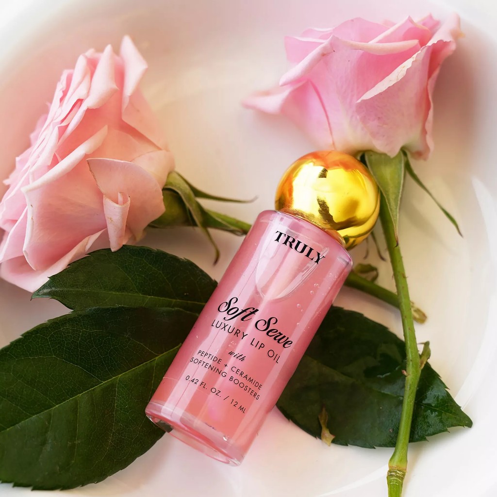 Soft Serve Luxury Lip Oil de la marca Truly, un aceite labial voluminizador con péptidos y ceramidas, aroma a fresa y un tinte rosa suave.