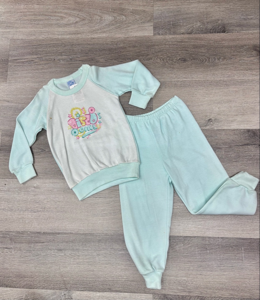 Este conjunto de pijama celeste para bebé marca Pillin cuenta con una sudadera estampada "Disco Girl" y monos a juego.