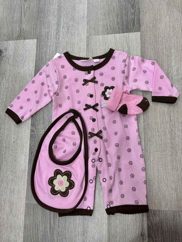 Este pijama rosado de bebé, marca Arenas Serrano, cuenta con un aplique de flor marrón y detalles de lazos.