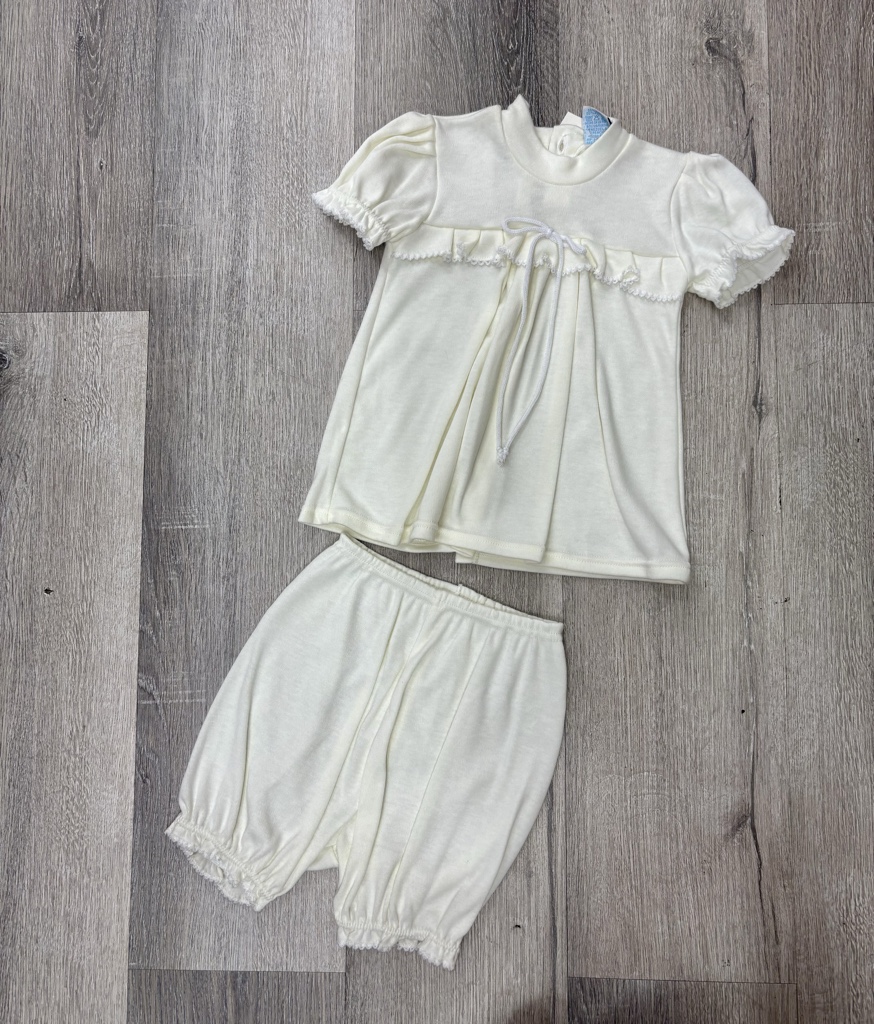 Este conjunto de ajuar blanco para bautizo de niña incluye una blusa delicada y pantalones bombachos estilo bloomer.