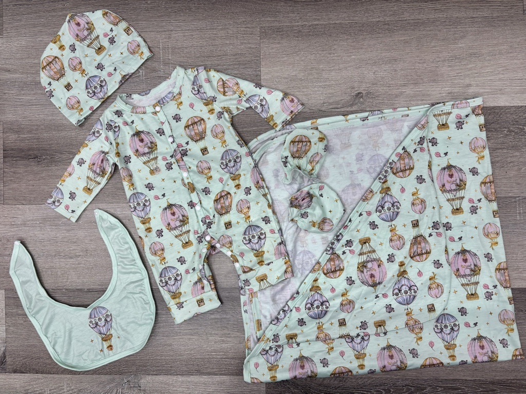 Set de 5 piezas gorro manoplas babero manta y este enterizo de Atelier Choux cuenta con un estampado de globos aerostáticos estilo parisino y está confeccionado en algodón orgánico