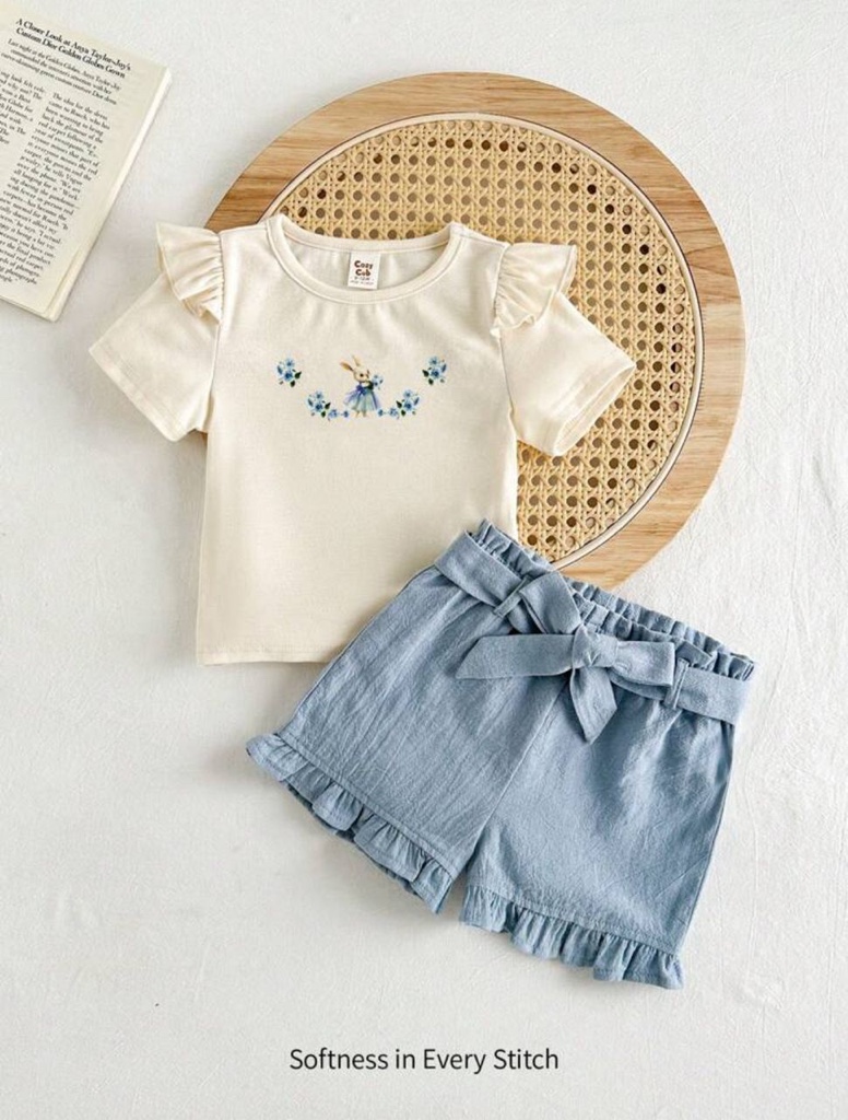 Este conjunto de den las mangas y un tierno estampado de conejito con flores, combinada con unos shorts azules de cintura elástica y lazo decorativo.