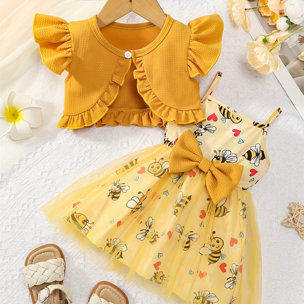 Este vestido de bebé amarillo presenta un estampado de abejas y un lazo decorativo.