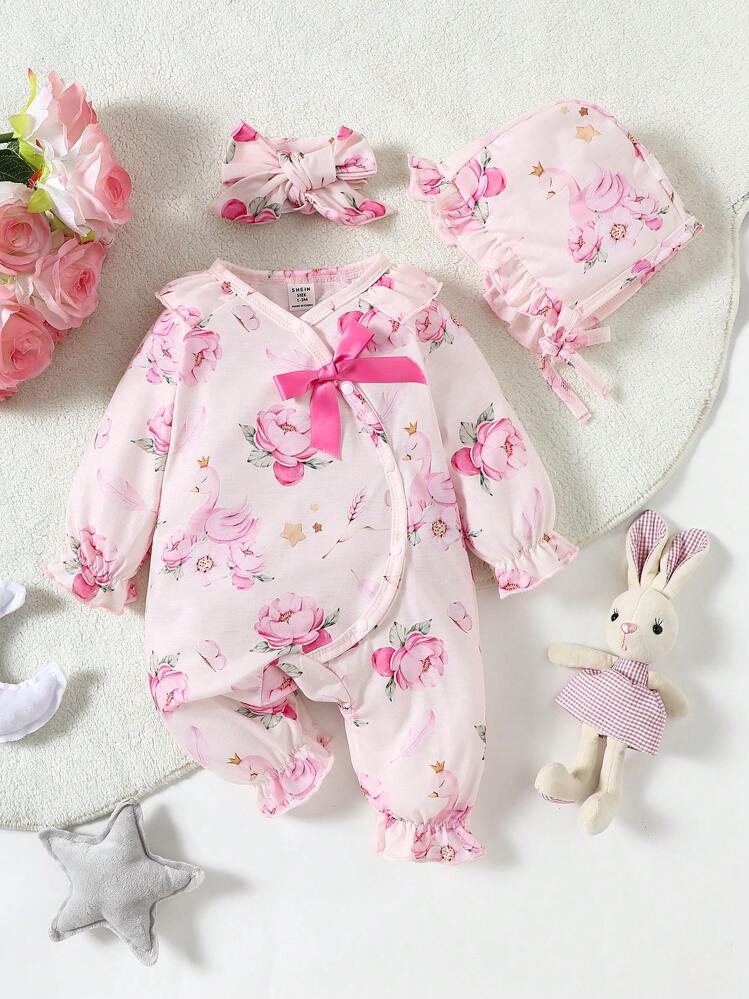 Enterizo de bebé destaca por su estampado de cisnes y flores rosadas con un lazo rosa brillante en el pecho.