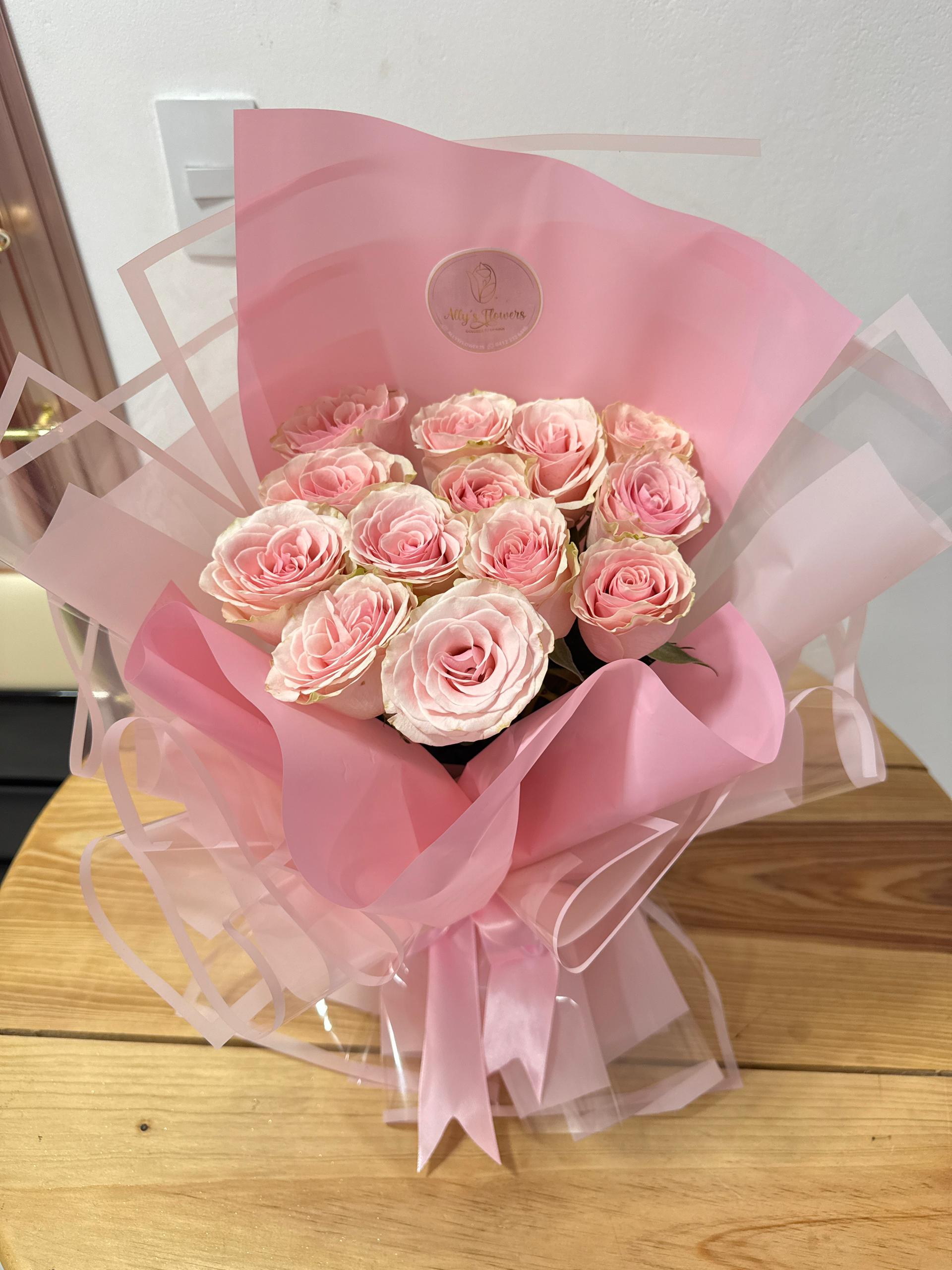 Ramo de 12 rosas rosadas envuelto en papel rosa