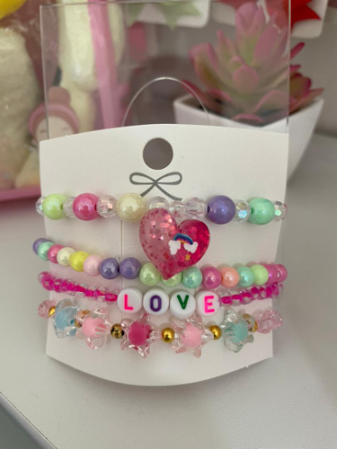 Set de 4 pulseras tonos rosados con dijes de estrella y corazones