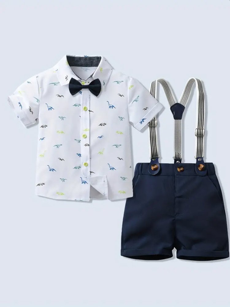 Traje de niño, traje de short azul, camisa blanca con dinosaurios en azul, gris y verde, tirante blanco con rayas negras, corbatín en negro
